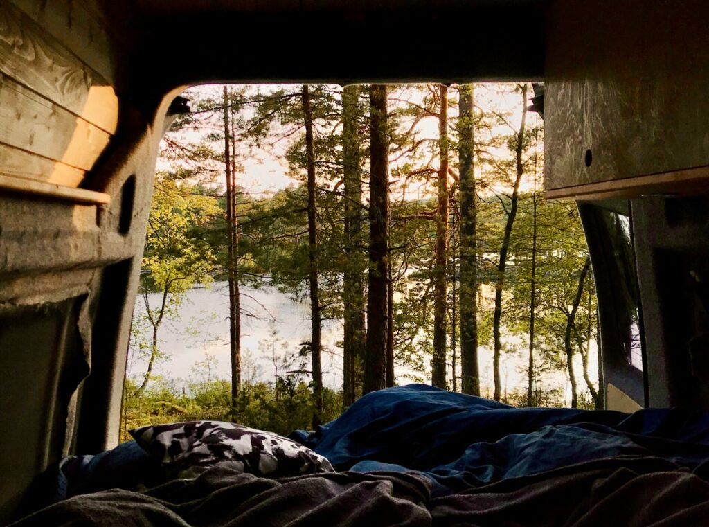 view from inside a camper van outside; with green trees and a lake in the background